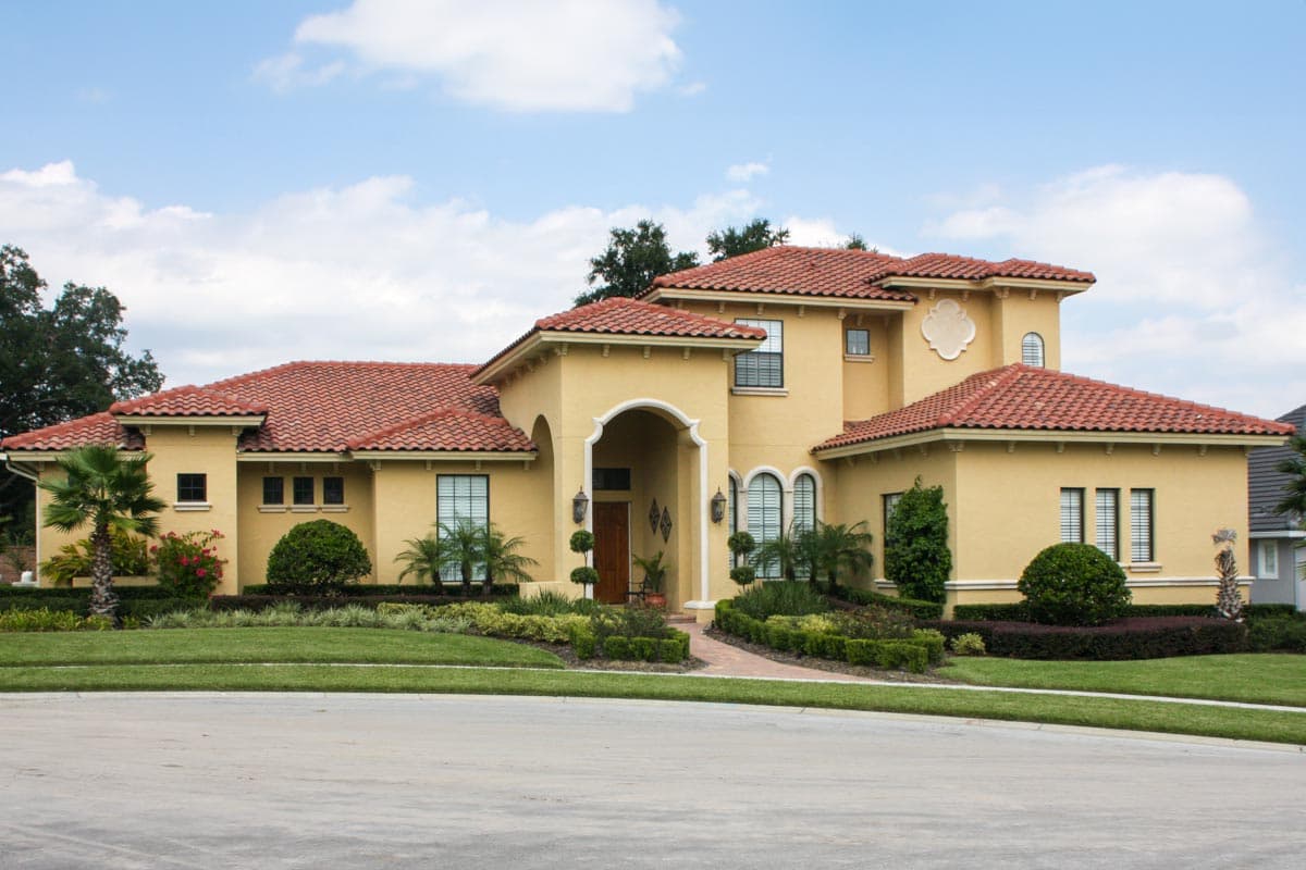 House plan exterior with Mediterranean architectural style, red tile roof, arched entryway, and multiple gables.