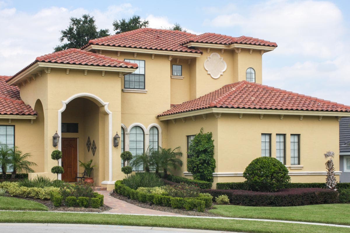House plan exterior shows a two-story Mediterranean style home with tile roof, arched entryway, and landscaped grounds.