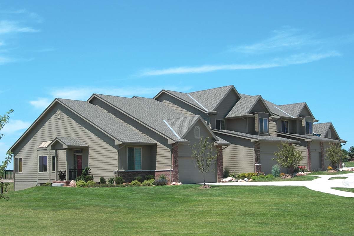 House plan exterior showing a multi-story dwelling with gabled dormers, multiple garages, and a covered entry.
