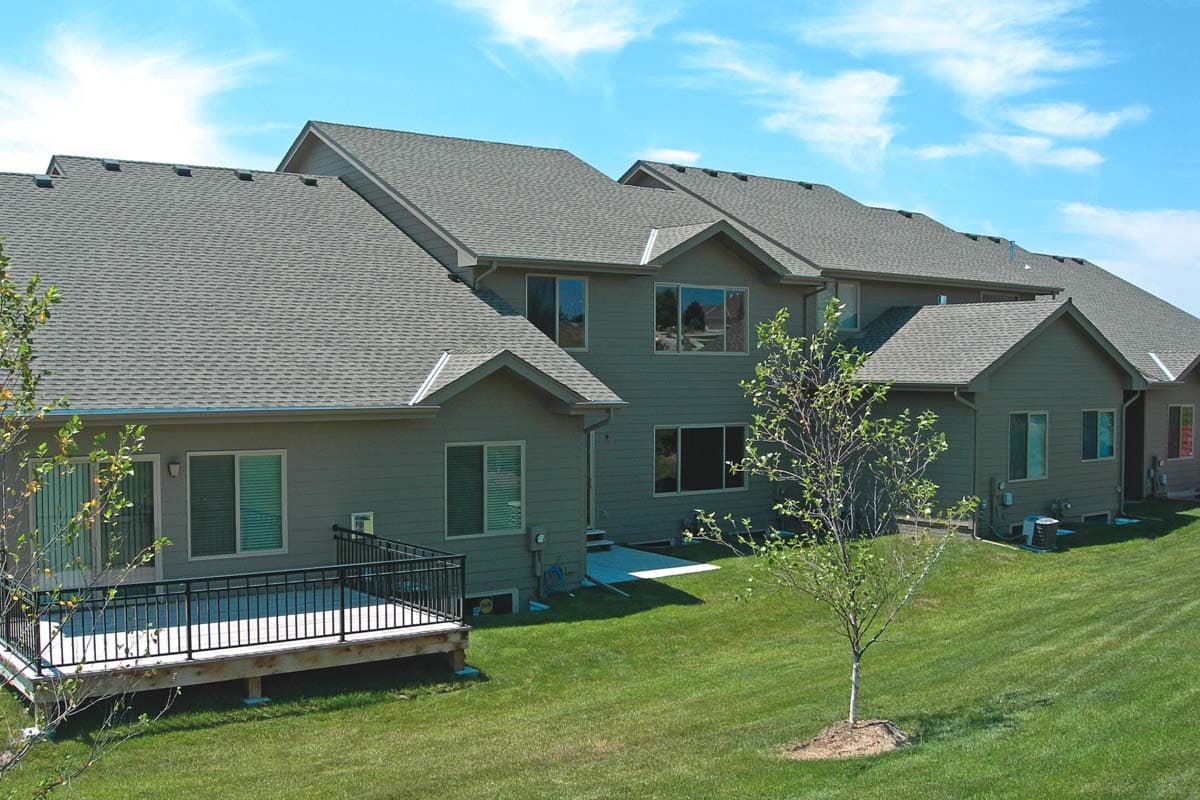 House plan exterior with stepped rooflines, multiple gables, and a large rear deck.