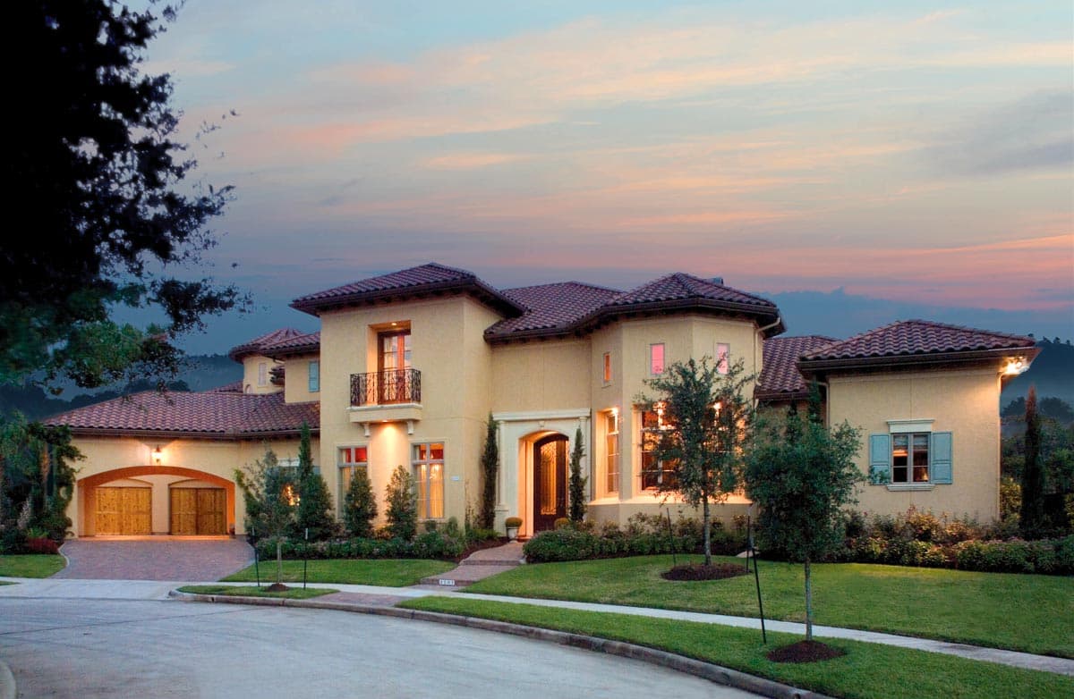 House plan exterior: Mediterranean style two-story home with tile roof, arched entryway, stucco finish, and a triple garage.