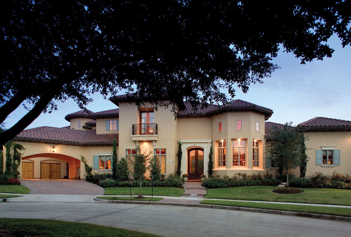 House plan exterior with Mediterranean style, two stories, arched porte-cochere, and wrought iron balcony.