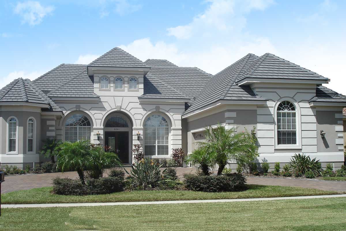 House plan exterior: one-story home with arched entry, multiple gables, tile roof, and garage.