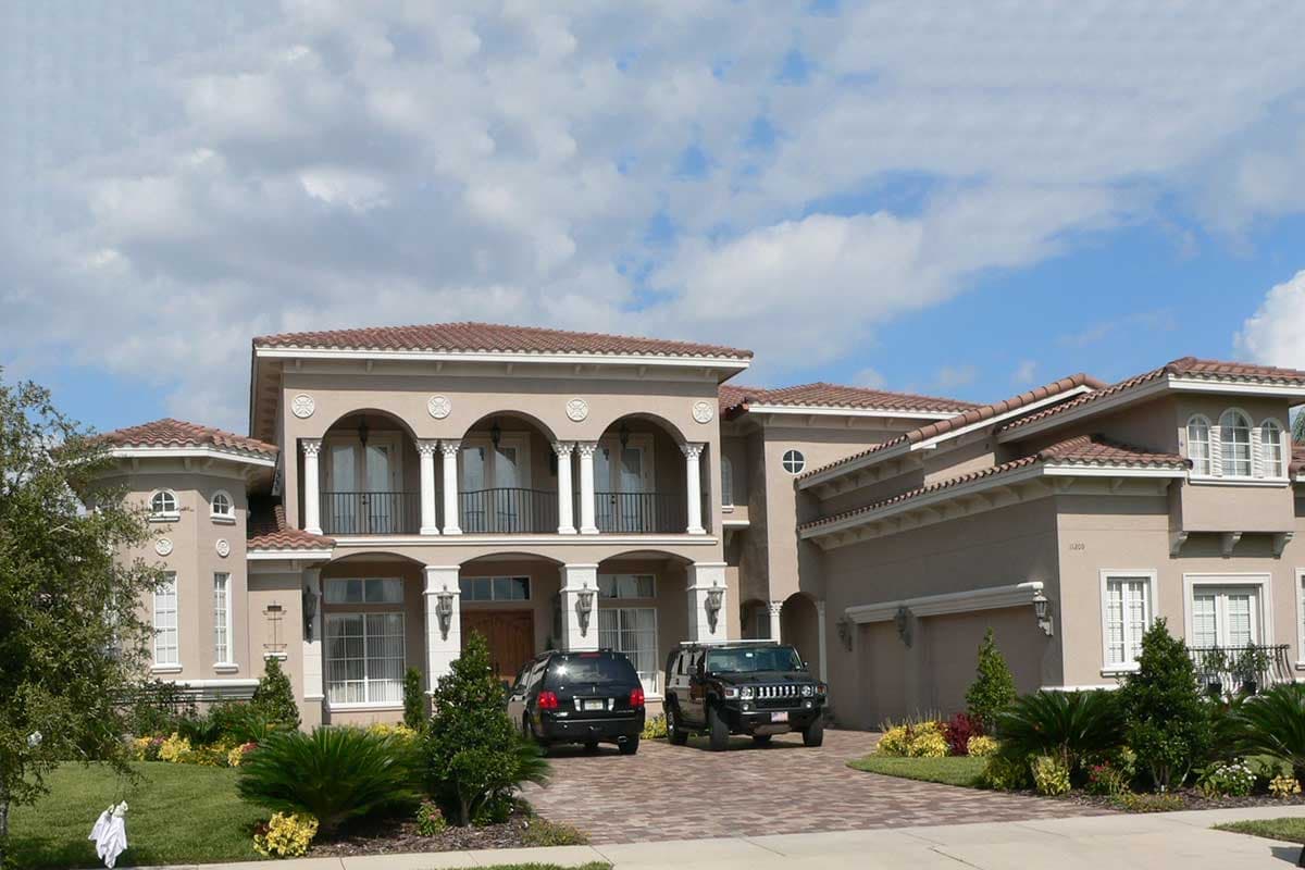 House plan exterior featuring a two-story Mediterranean style. Features include arched loggia, clay tile roof, and a side-entry garage.