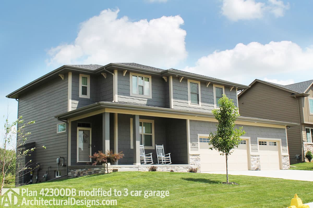 House plan exterior: Two-story home with a covered front porch, gabled rooflines, and a three-car garage.