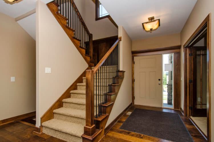 Interior entryway with wood staircase, wood flooring, and front door with glass sidelight.