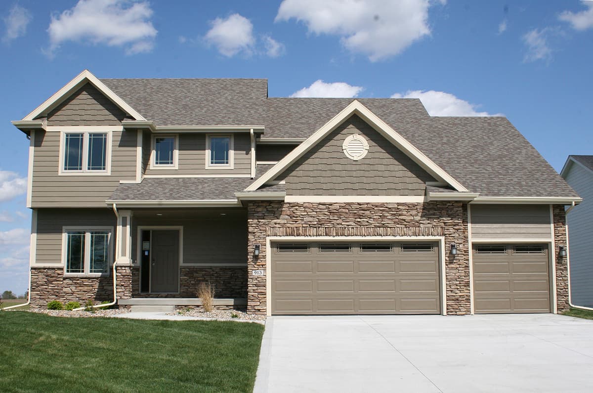 Two-story house plan exterior with stone accents, gables, covered entry, and a triple-car garage.