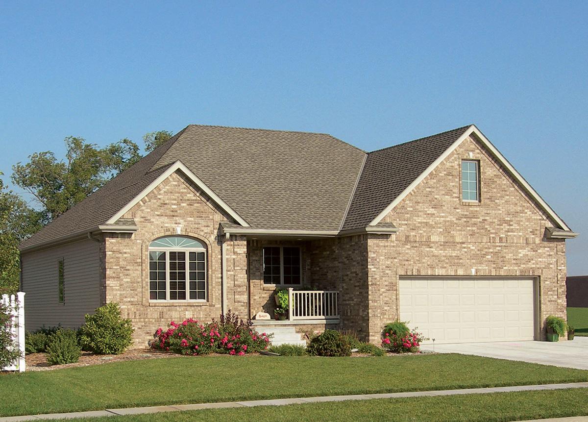 House plan exterior: Brick facade, one-story home with attached two-car garage, arched window, and covered front porch.