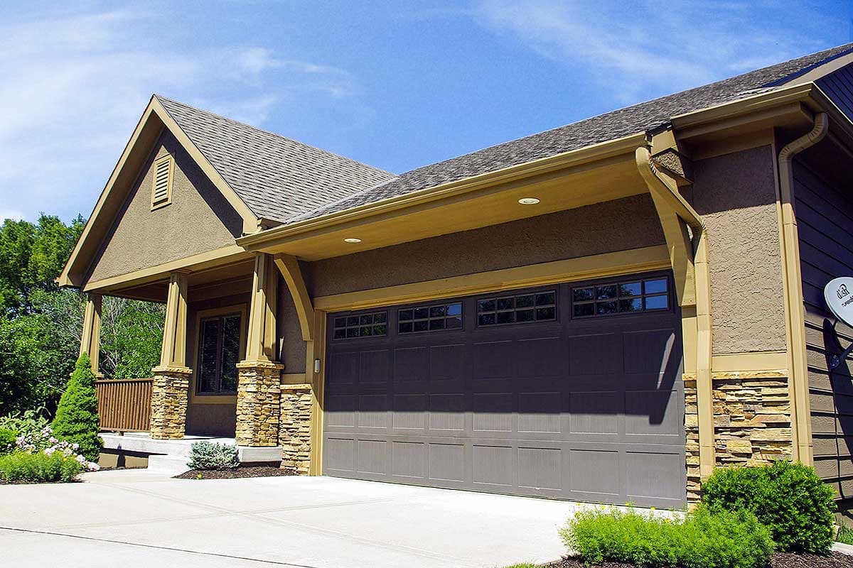 Craftsman style house plan exterior with covered porch, stone accents, and a multi-pane garage door.