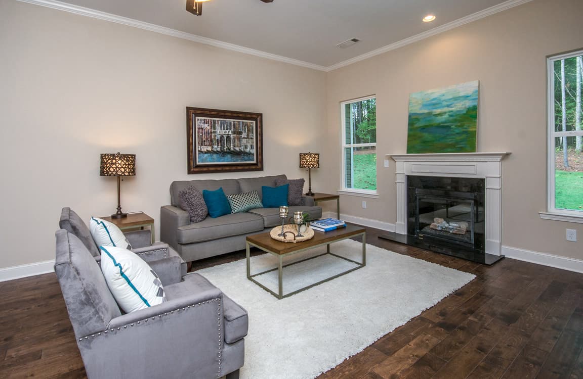 Living room with fireplace, seating area, coffee table, and large windows.