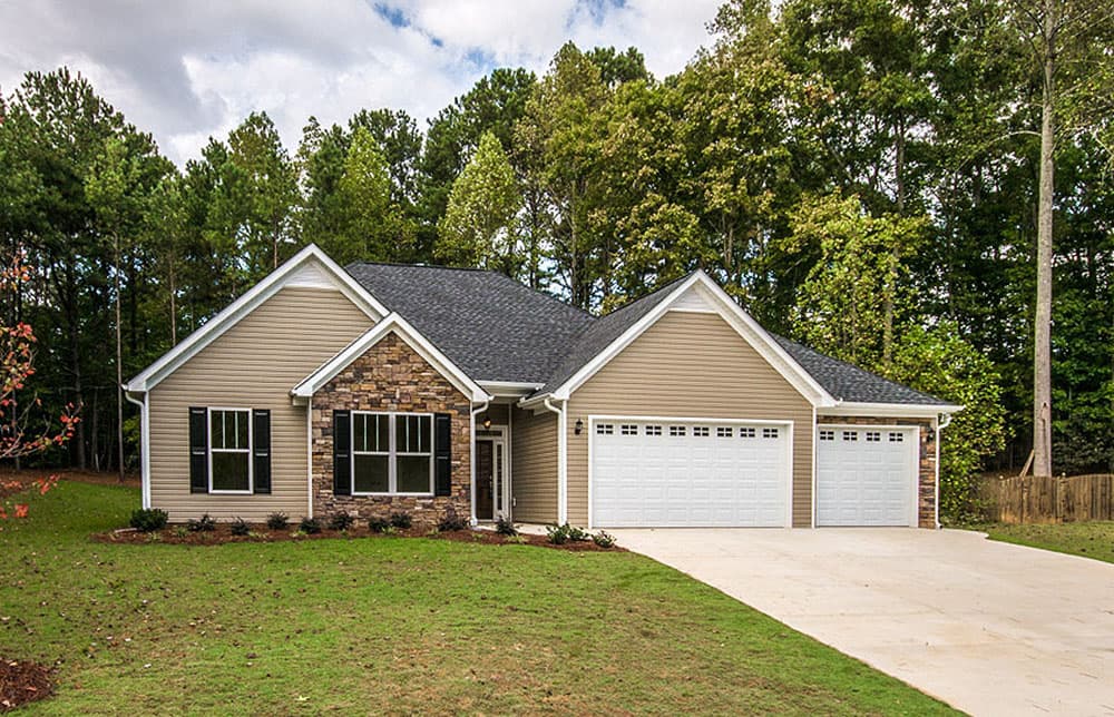 House plan exterior: Ranch style, tan siding, stone accents, gable roof, two-car garage, and a covered entry.