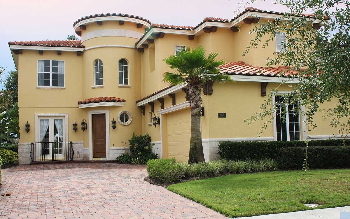 Two-story Mediterranean style house plan with stucco exterior, tile roof, arched windows, turret, and attached garage.