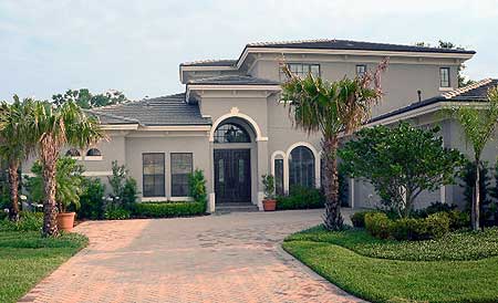 House plan exterior of a two-story home with a tiled roof, arched entryway, and stucco facade.