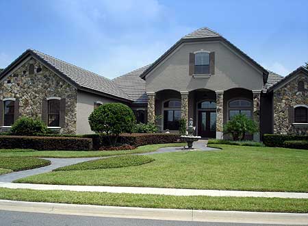 House plan exterior: One-story home with stone accents, arched windows, a covered entry with columns, and a pitched tile roof.