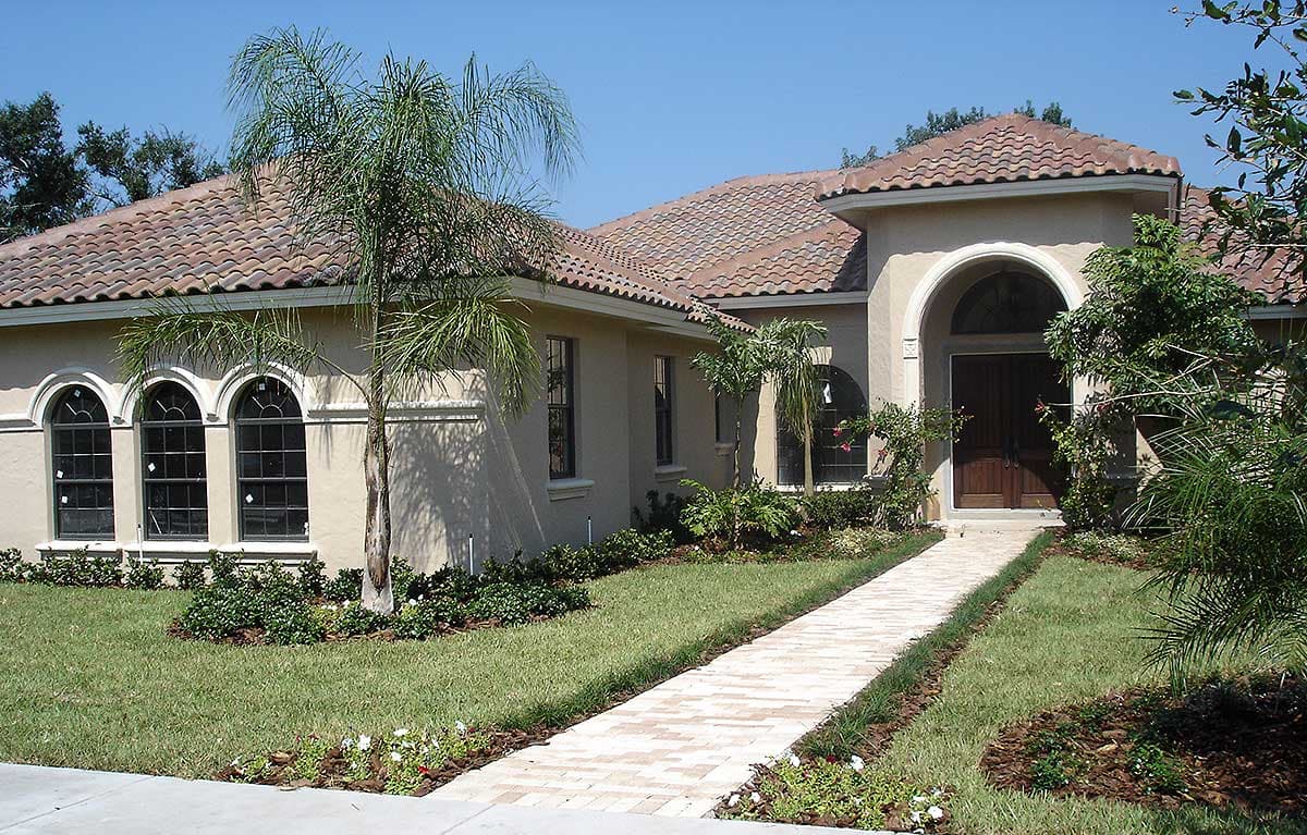 House plan exterior featuring a tiled roof, arched entry, and arched windows.