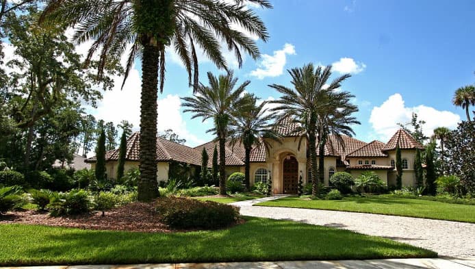 House plan exterior with a stucco finish, tile roof, arched entryway, and a multi-level design with turrets.