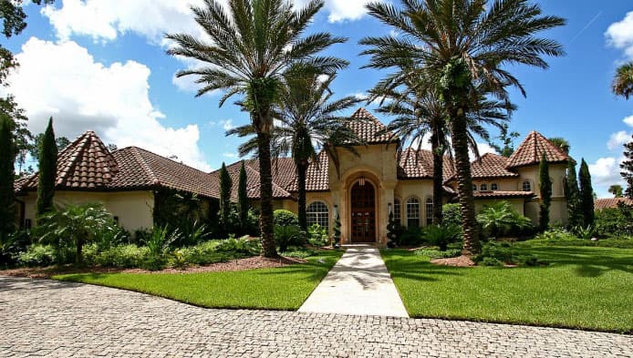 Mediterranean style house plan exterior with arched entrance, tiled roofs, multiple gables, and central tower.