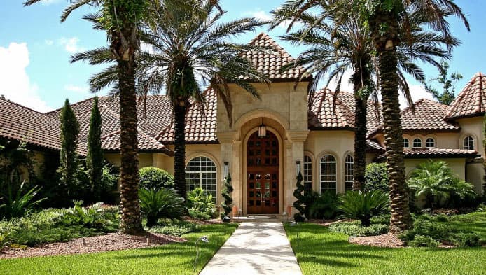 Mediterranean style house plan exterior with arched entry, tile roof, and courtyard entry.