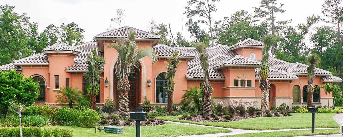 House plan exterior: Mediterranean style, stucco walls, tile roof, arched entry, multiple gables, and turrets.