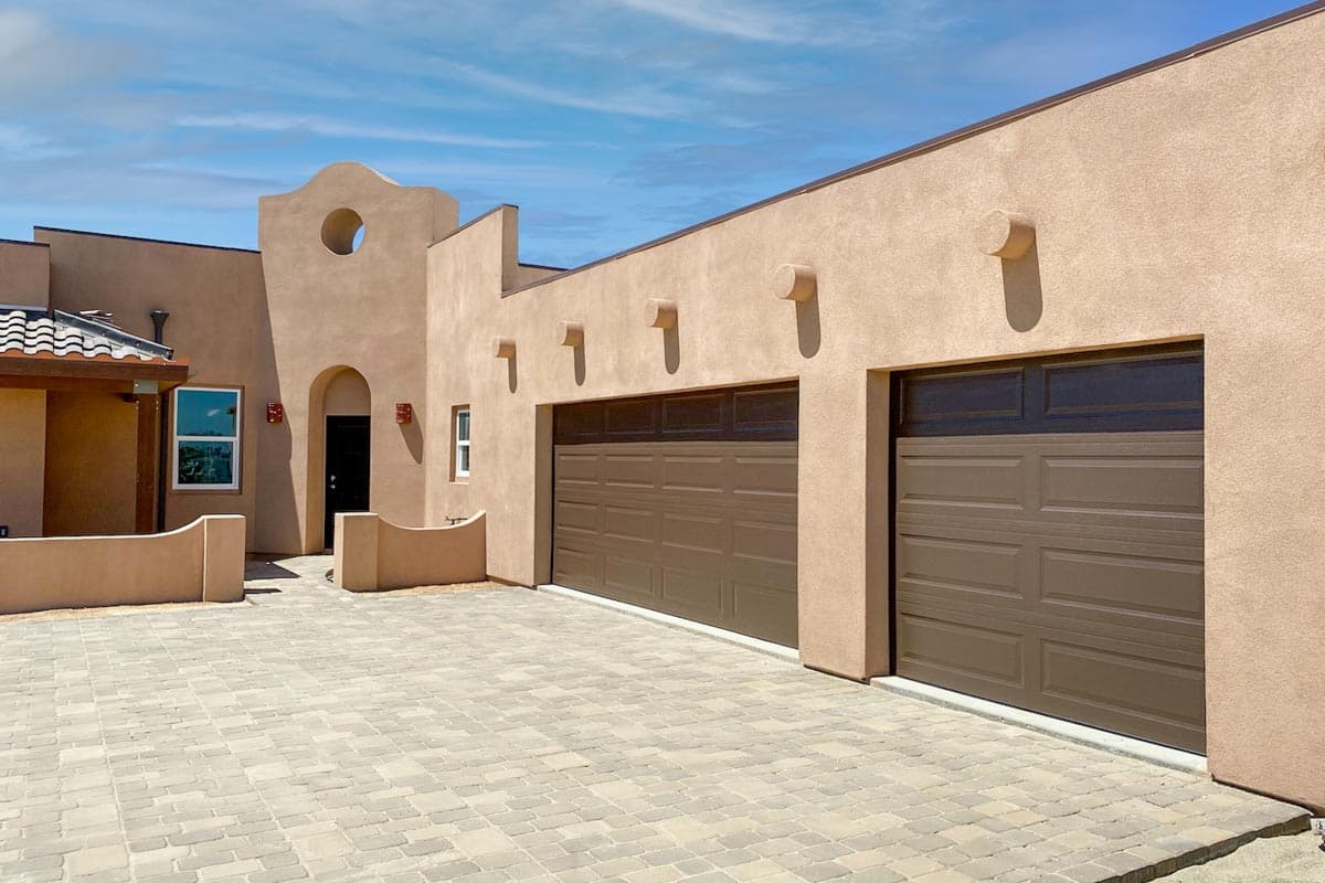 Southwestern style house plan exterior with arched entry, round window, two-car garage, and stucco walls.
