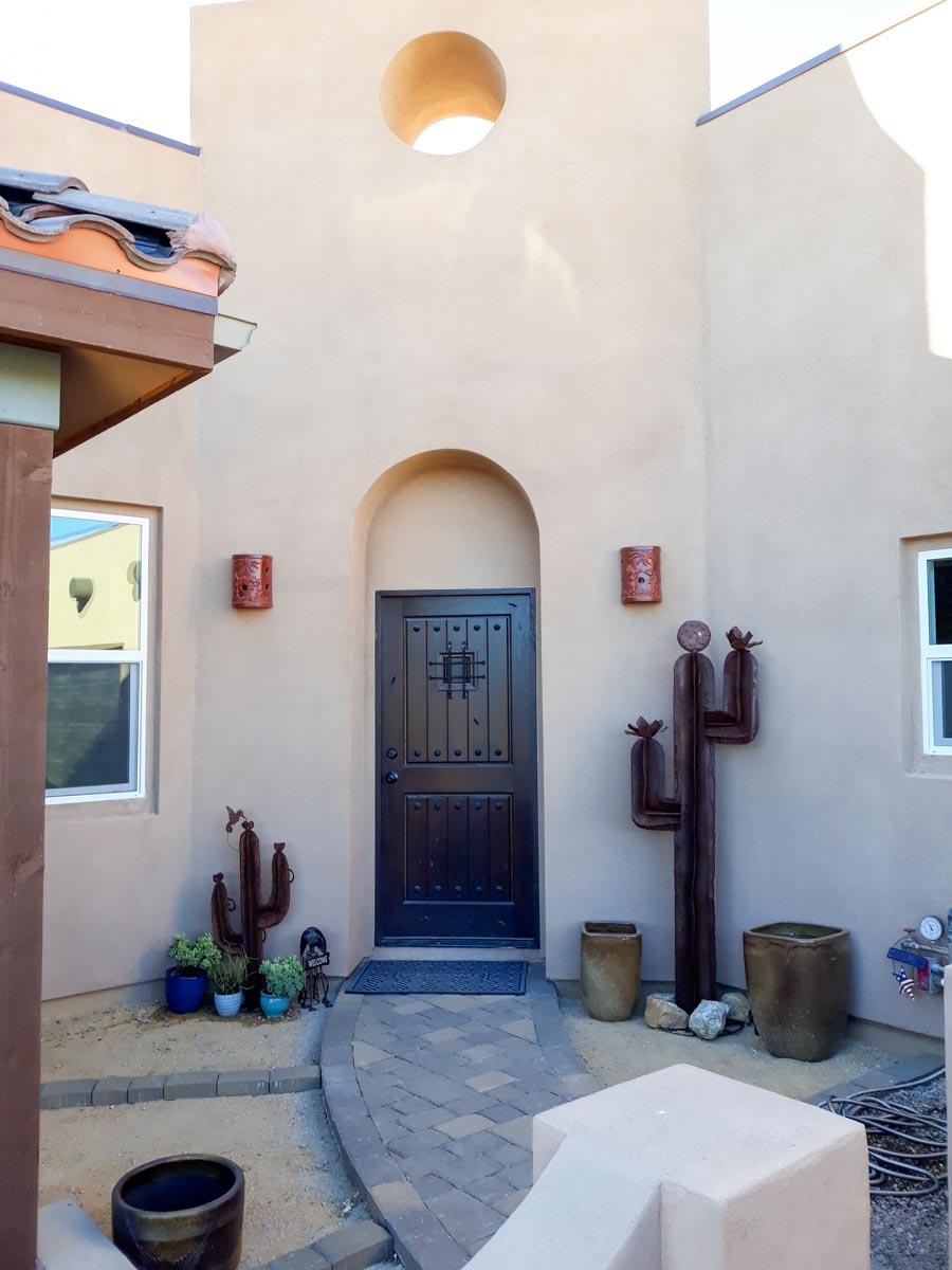 House plan exterior featuring an arched entryway, dark wood door, circular window, and tiled roof.