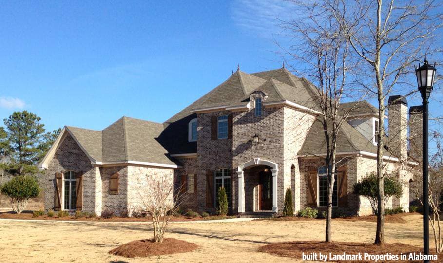 House plan exterior: two-story brick residence with arched entryway, multiple gables, dormers, and prominent chimneys.