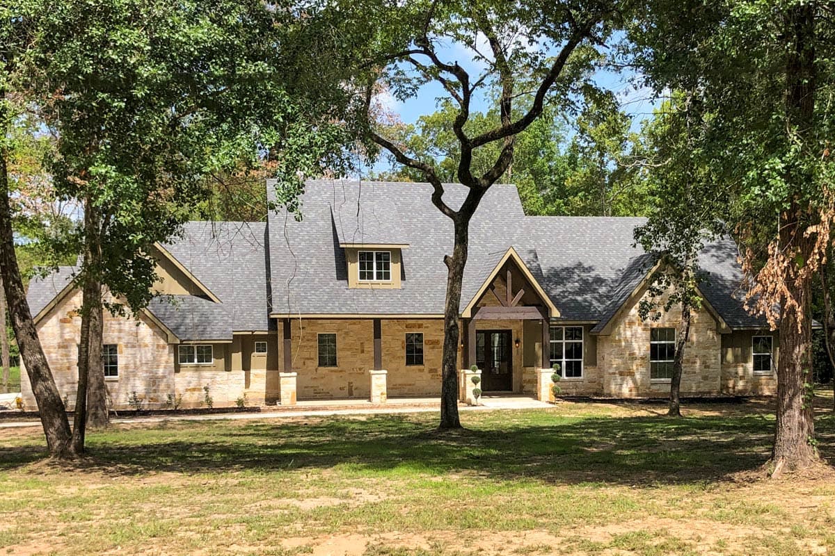 House plan exterior. Craftsman style, single story. Features include a front porch with exposed beams, gables, and stone veneer facade.