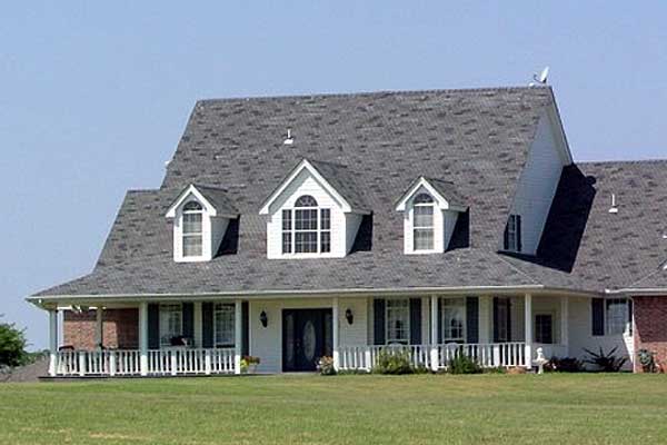 House plan exterior: Two-story home with wraparound porch, dormer windows, and a prominent gable.