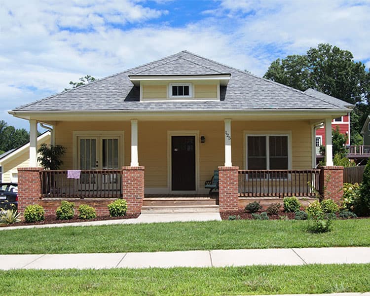 House plan exterior: Craftsman style, one story, with a large covered front porch, brick piers, and a dormer.