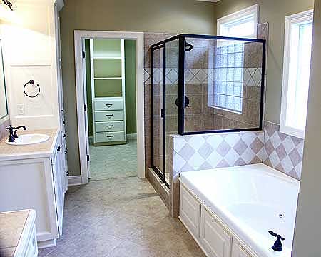 Master bathroom with double vanity, glass-enclosed shower, soaking tub, and walk-in closet.