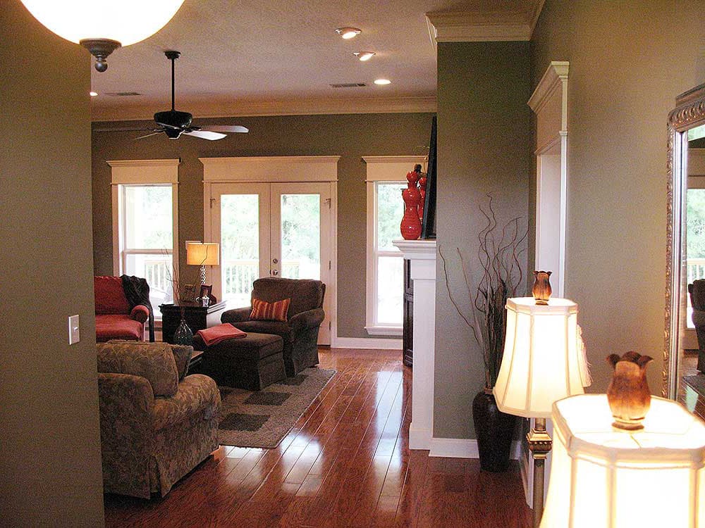 Living room interior with fireplace, double doors, ceiling fan, and hardwood floors.