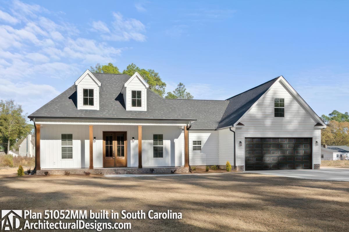 House plan exterior: Modern Farmhouse, one story, covered porch with wood columns, double front doors, dormers, and attached garage.