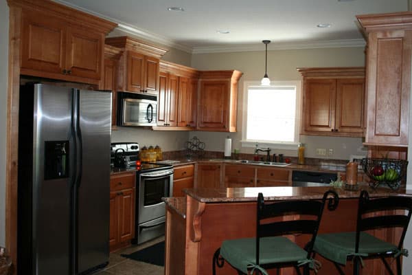 Kitchen featuring stainless steel refrigerator, range, microwave, granite countertops, and wood cabinetry with crown molding.