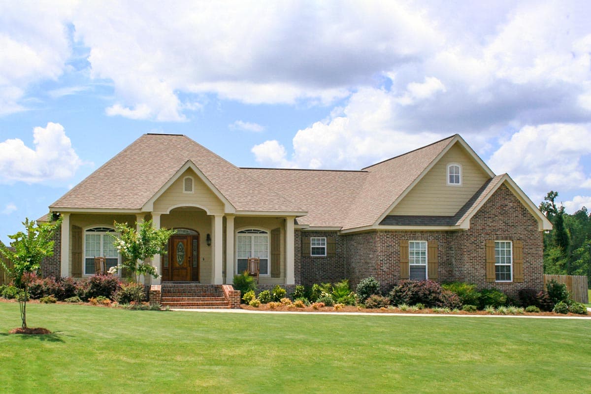 House plan exterior: One-story home with brick and siding, prominent gabled entrance, covered porch, and multiple rooflines.