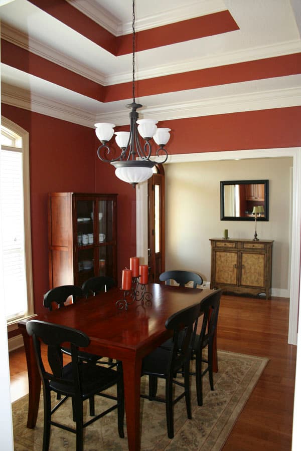Dining room with coffered ceiling, dark wood table and chairs, buffet, and chandelier.