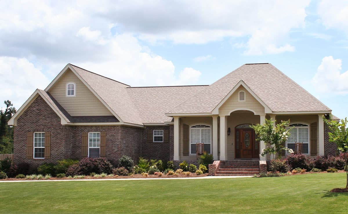 House plan exterior: One-story home with brick and siding, covered entry porch with columns, and gabled dormers.