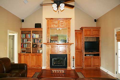 Great room with vaulted ceiling, fireplace, built-in bookshelves, and entertainment center.