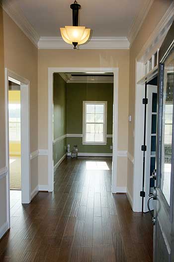 Interior view of a house entryway with dark wood floors and openings to a green room and yellow room.
