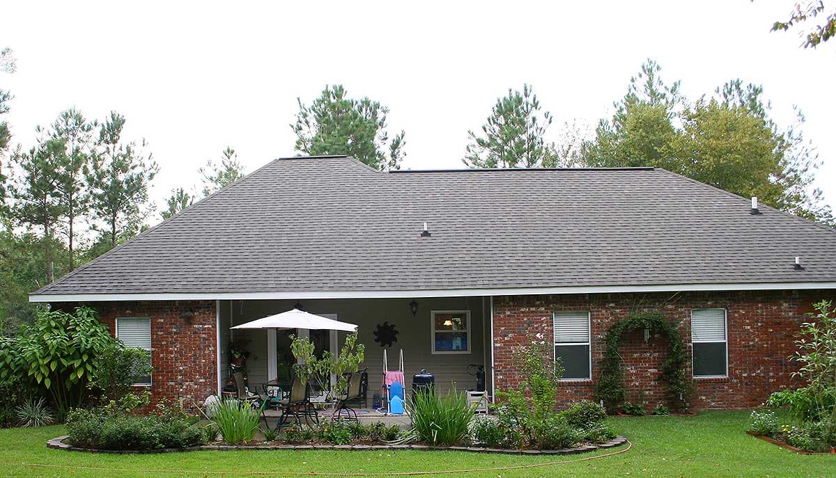 House plan exterior of a one-story brick home with a covered patio, peaked roof, and varied window styles.