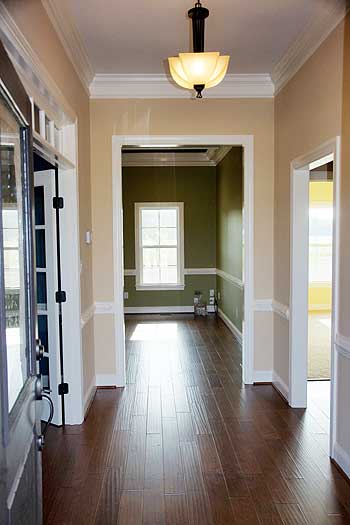 Interior view of a hallway with dark wood floors, crown molding, and openings to other rooms.