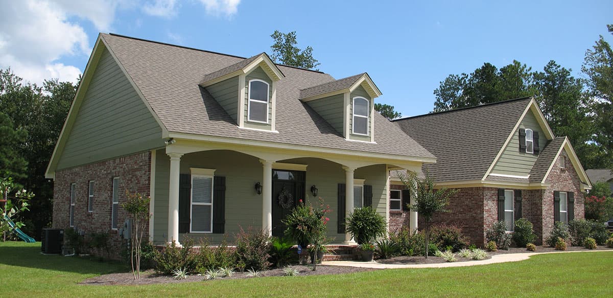 House plan exterior: Two-story home with prominent gabled dormers, brick and siding facade, and covered entry porch supported by columns.