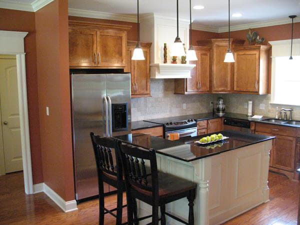 Kitchen with wood cabinets, granite countertops, stainless steel refrigerator, and center island with seating.