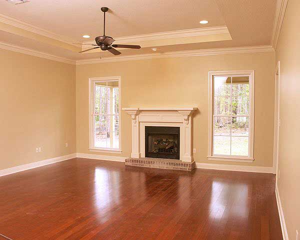 Interior view of a living room with fireplace, coffered ceiling, ceiling fan, and hardwood floors.