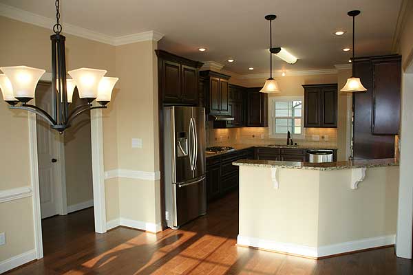 Kitchen with dark wood cabinets, stainless steel refrigerator, granite countertops, and an island.