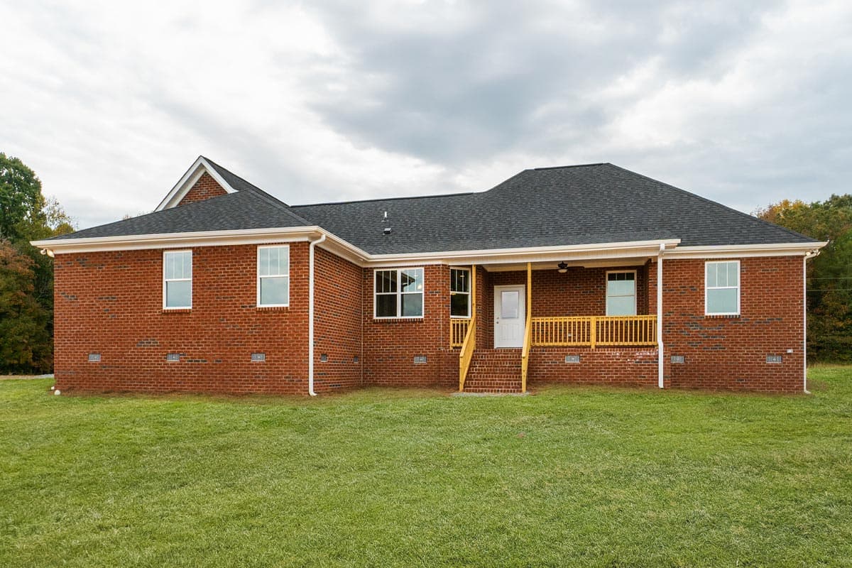 House plan exterior: One-story brick residence with a gabled roof, covered porch with yellow railing, and multiple windows.
