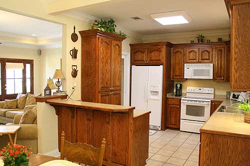 Kitchen with oak cabinets, white appliances, built-in microwave, and a peninsula with seating.