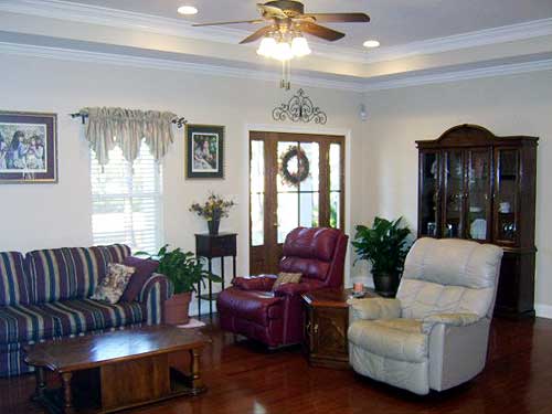 Living room interior with striped sofa, two recliners, wood coffee table, china cabinet, and double glass doors.