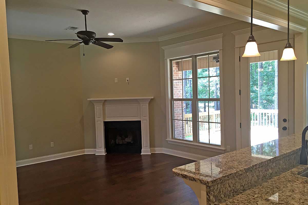 Living area with fireplace, ceiling fan, large window overlooking deck, and granite counter island.