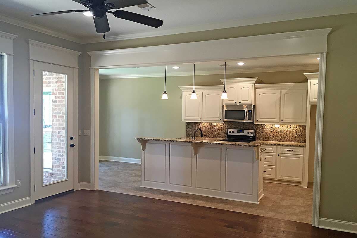 Kitchen with white cabinets, granite island with pendant lights, and stainless steel appliances, open to dining area.