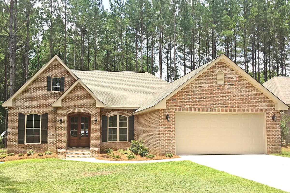 House plan exterior, brick finish, gable rooflines, arched windows, double-door entry, and attached garage.